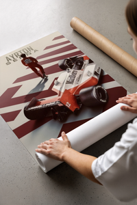 Person kneeling on a concrete floor unrolling the Senna McLaren F1 race car print