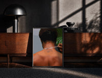 Black-framed Back View Fastening a Necklace print on the floor in front of a dark wooden console