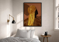 Back View in a Gold Durag print in a black frame above a bed with striped linens, a brass wall lamp and a sunlit window