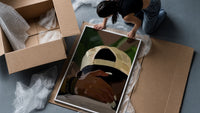 Backwards Cap with an Embracing Hand framed print being unpacked from protective bubble wrap and a box