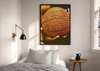 Basketball Covered in Handwriting print in a black frame above a bed with striped linens