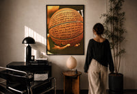 Basketball Covered in Handwriting print in a black frame on a sunlit plaster wall, a woman looking on beside a mushroom lamp