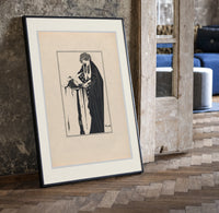 Woman holding severed head print in a black frame leaning beside a vintage door on parquet
