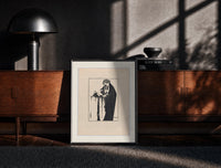 Black-framed Woman holding severed head print on a moody console with designer coffee-table books