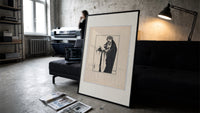 Woman holding severed head print in a slim black frame leaning on a dark sofa in a concrete print studio