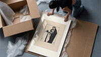 Woman holding severed head framed print being unpacked from protective bubble wrap and a box