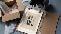 Two Art Nouveau figures embracing framed print being unpacked from protective bubble wrap and a box