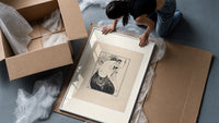 Two elegant women in flowing gowns framed print being unpacked from protective bubble wrap and a box