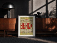 Black-framed Berck beach seaside resort advertisement print on a moody console with designer coffee-table books