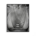 Black and white close-up of a Chanel CC pendant necklace resting over a graffiti-detailed bikini top