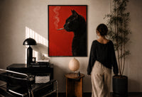 Black Cat Smoking a Cigarette print in a black frame on a sunlit plaster wall, a person looking on beside a mushroom lamp