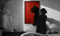 Black Cat Smoking a Cigarette print in a slim black frame being hung on a sunlit wall in a monochrome room