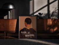 Black-framed Black Is Beautiful Jacket print on the floor in front of a dark wooden console