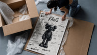 Black KAWS Companion figure standing framed print being unpacked from protective bubble wrap and a box