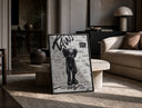 KAWS Companion figure standing print in a black frame leaning on a travertine table in a sunlit lounge