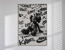 Black KAWS Companion figure sitting poster in a slim frame on a bright wall with soft window light