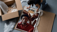 Black Man Having His Hair Braided framed print being unpacked from protective bubble wrap and a box