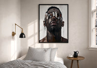 Black Man in Metallic Sunglasses print in a black frame above a bed with striped linens