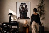 Black Man in Metallic Sunglasses print in a black frame on a sunlit plaster wall, a woman looking on beside a mushroom lamp