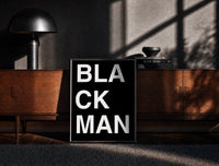 Black-framed Black Man Lettering print on the floor in front of a dark wooden console