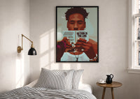 Black Man Reading a Paperback print in a black frame above a bed with striped linens, a brass wall lamp and a sunlit window