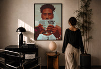 Black Man Reading a Paperback print in a black frame on a sunlit plaster wall, a woman looking on beside a mushroom lamp