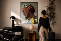 Black Man with Colorful Hair Clips print in a black frame on a sunlit plaster wall, a woman looking on beside a mushroom lamp
