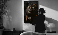 Black Man with Gold Drop Earrings print in a slim black frame being hung on a sunlit wall in a monochrome room