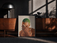Black-framed Black Man with Green Hair print on the floor in front of a dark wooden console