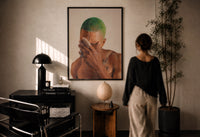 Black Man with Green Hair print in a black frame on a sunlit plaster wall, a woman looking on beside a mushroom lamp
