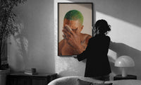 Black Man with Green Hair print in a slim black frame being hung on a sunlit wall in a monochrome room