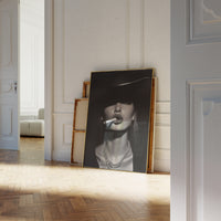Large gold-framed black and white fashion portrait leaning against a white paneled wall in a sunlit room