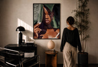 Black Woman with Tropical Leaves print in a black frame on a sunlit wall with a viewer