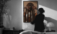 Black Woman Holding Her Braids print in a slim black frame being hung on a sunlit wall in a monochrome room