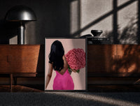 Black-framed Black Woman Holding Pink Roses print on the floor in front of a dark wooden console
