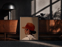 Black-framed Black Woman in Red Baseball Cap print on the floor in front of a dark wooden console