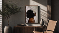 Black Woman with a Curly Puff poster framed above a fluted sideboard beside a potted tree