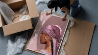 Black Woman with a Pink Headscarf framed print being unpacked from protective bubble wrap and a box