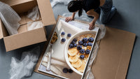 Blueberry Banana Oatmeal Bowl framed print being unpacked from protective bubble wrap and a box