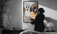 Blueberry Banana Oatmeal Bowl print in a slim black frame being hung on a sunlit wall in a monochrome room