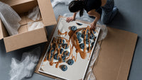 Blueberry Pancakes with Chocolate print in a slim black frame being hung on a sunlit wall in a monochrome room