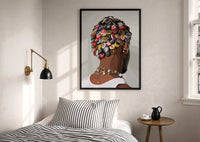 Bottle Cap Headpiece and Chunky Necklaces print in a black frame above a bed with striped linens