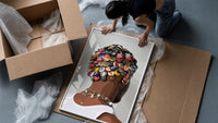 Bottle Cap Headpiece and Chunky Necklaces framed print being unpacked from protective bubble wrap and a box