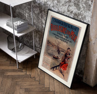Woman in traditional dress by seaside poster in a black frame leaning beside a shelf in a raw-plaster loft