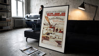 Breton fishing boat and coastal scenes print in a slim black frame leaning on a dark sofa in a concrete print studio