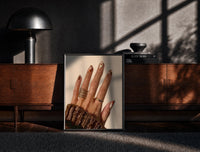 Black-framed Brown Almond Nails print on the floor in front of a dark wooden console