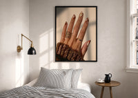 Brown Almond Nails print in a black frame above a bed with striped linens