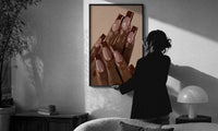 Brown French Tips print in a slim black frame being hung on a sunlit wall in a monochrome room