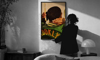 Brushing Waves in a Varsity Jacket print in a slim black frame being hung on a sunlit wall in a monochrome room
