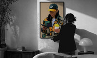 Camo Jacket and Takeaway Drink print in a slim black frame being hung on a sunlit wall in a monochrome room